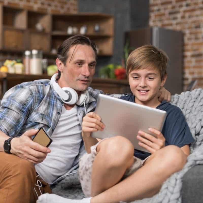 happy smiling father and son sitting on couch use FKPY7SN 800x800 - 7 Cool Things To Do With Your Kids At Home